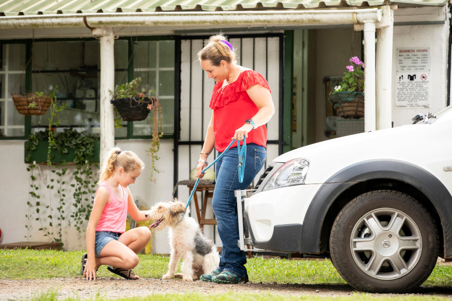 Woman with her daughter and their dog on the lawn in front of the office